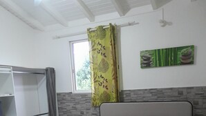 Ein Schlafzimmer mit einem Bett, einem Kleiderschrank, einem Fenster mit Vorhang und einer Wand mit einer Dekoration.