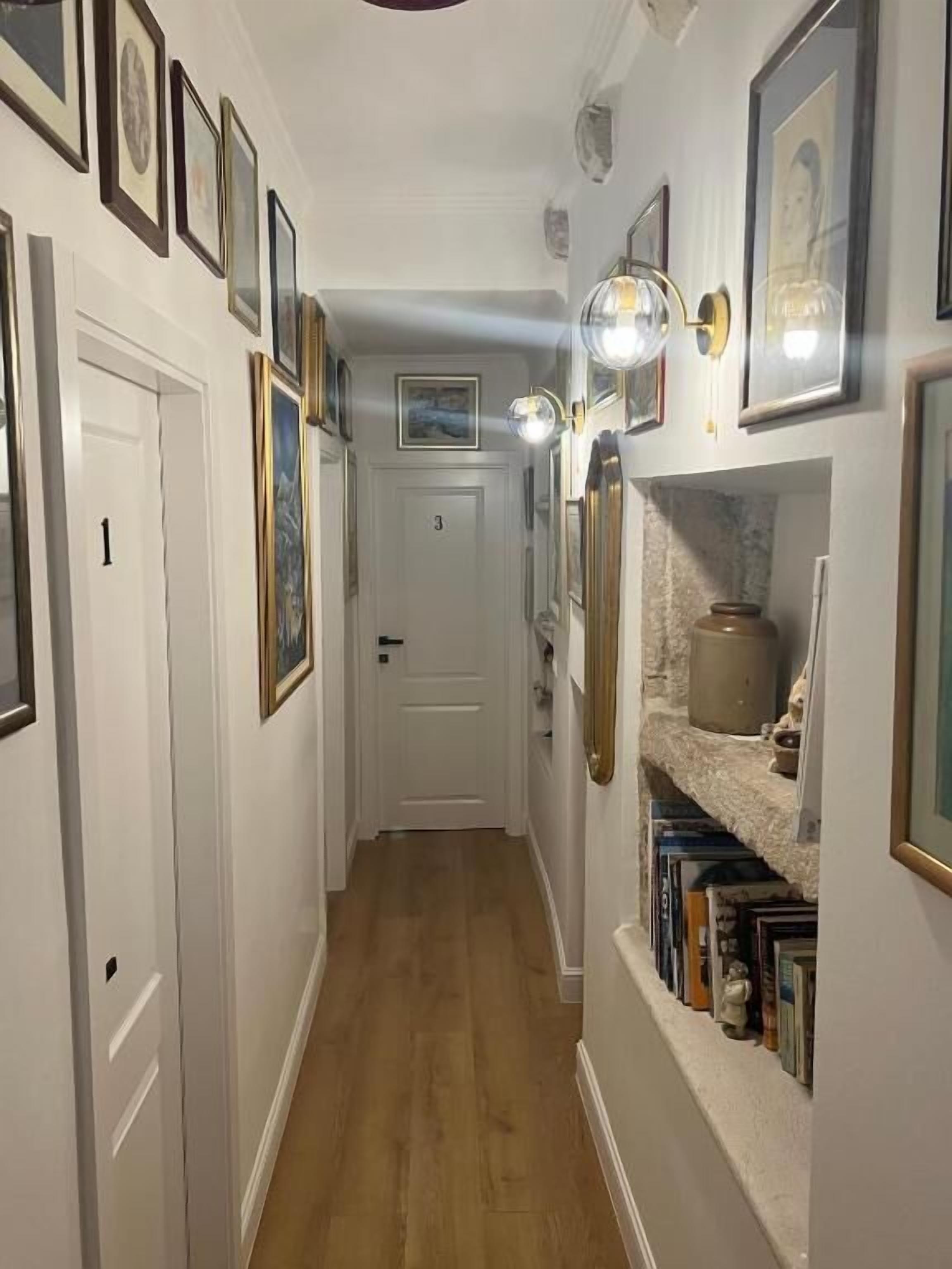A narrow hallway with wooden flooring, white walls, and a door marked with the number 3.