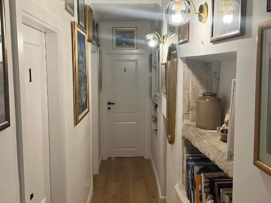 A narrow hallway with wooden flooring, white walls, and a door marked with the number 3.