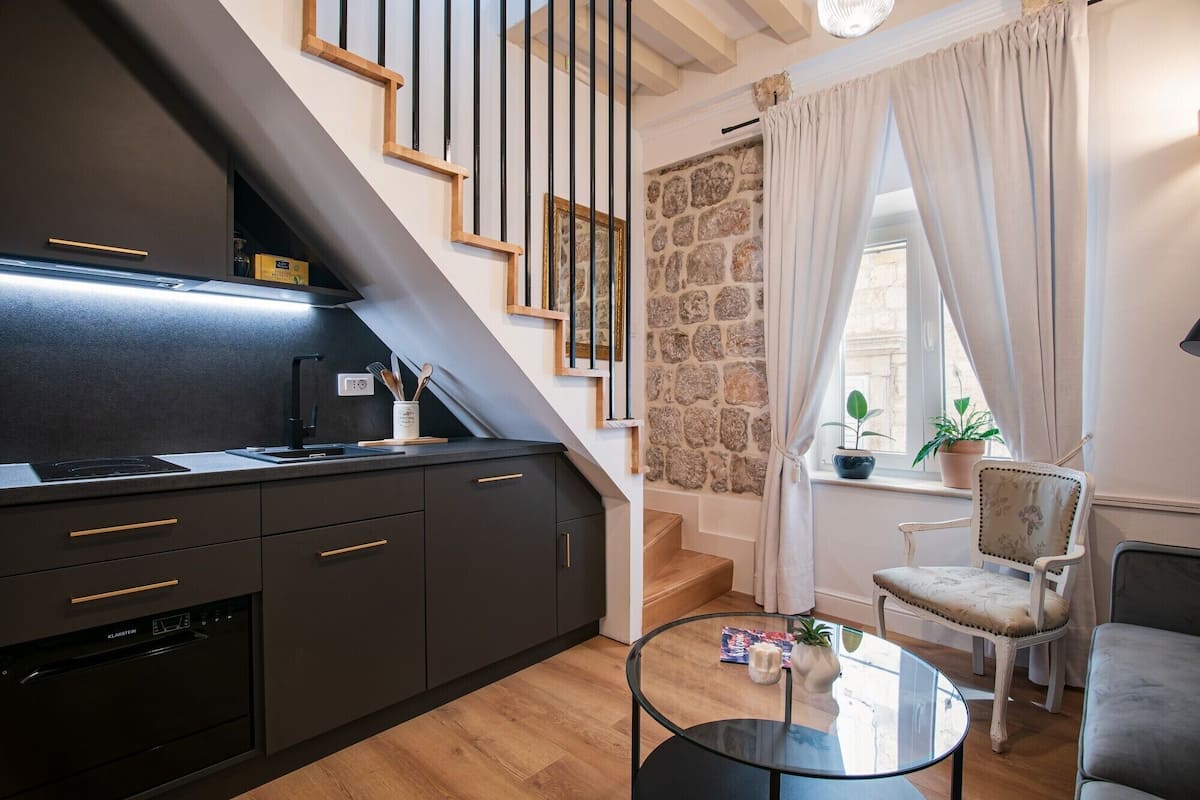 A modern kitchen with dark cabinetry, a built-in stove, and a glass-top coffee table.