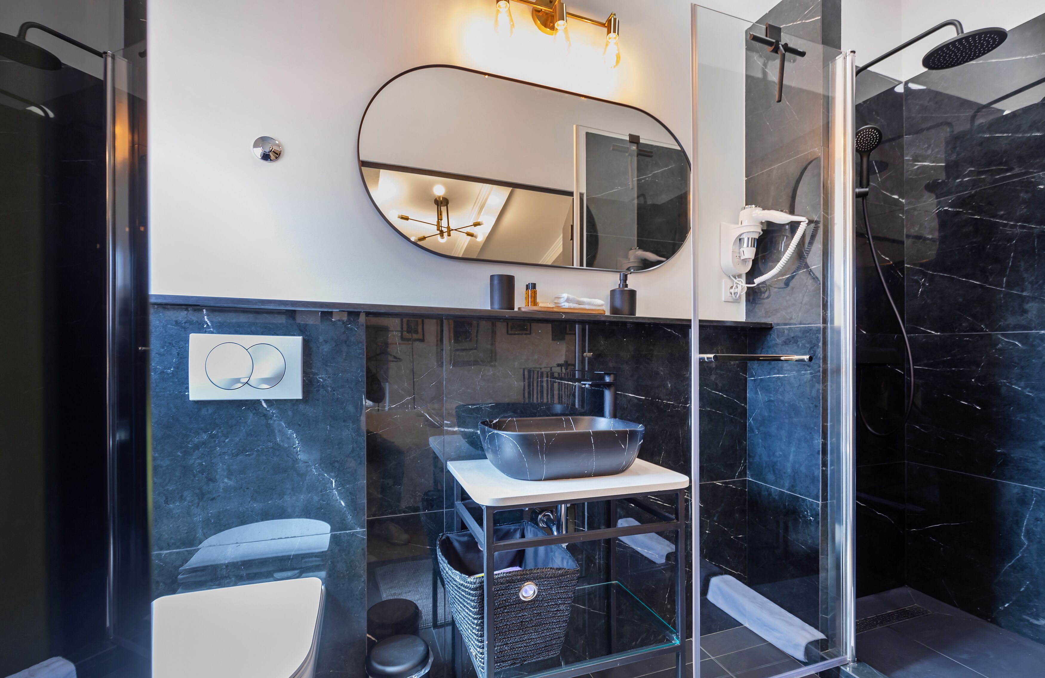 Un baño moderno con cabina de ducha de vidrio, un espejo grande y encimera de mármol.