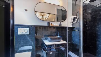 Un baño moderno con cabina de ducha de vidrio, un espejo grande y encimera de mármol.