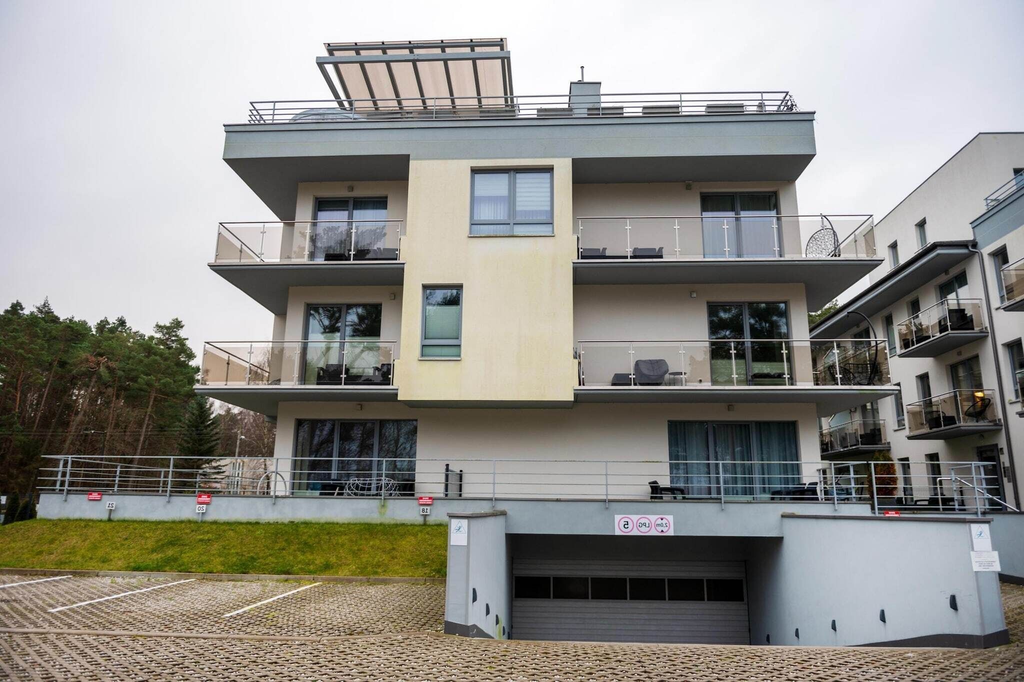 Un edificio residencial de varios pisos con balcones, ventanas grandes y acceso a un garaje.