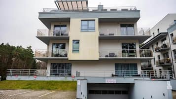 Un edificio residencial de varios pisos con balcones, ventanas grandes y acceso a un garaje.