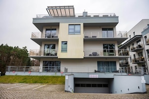 A multi-story residential building with balconies, large windows, and a garage entrance.