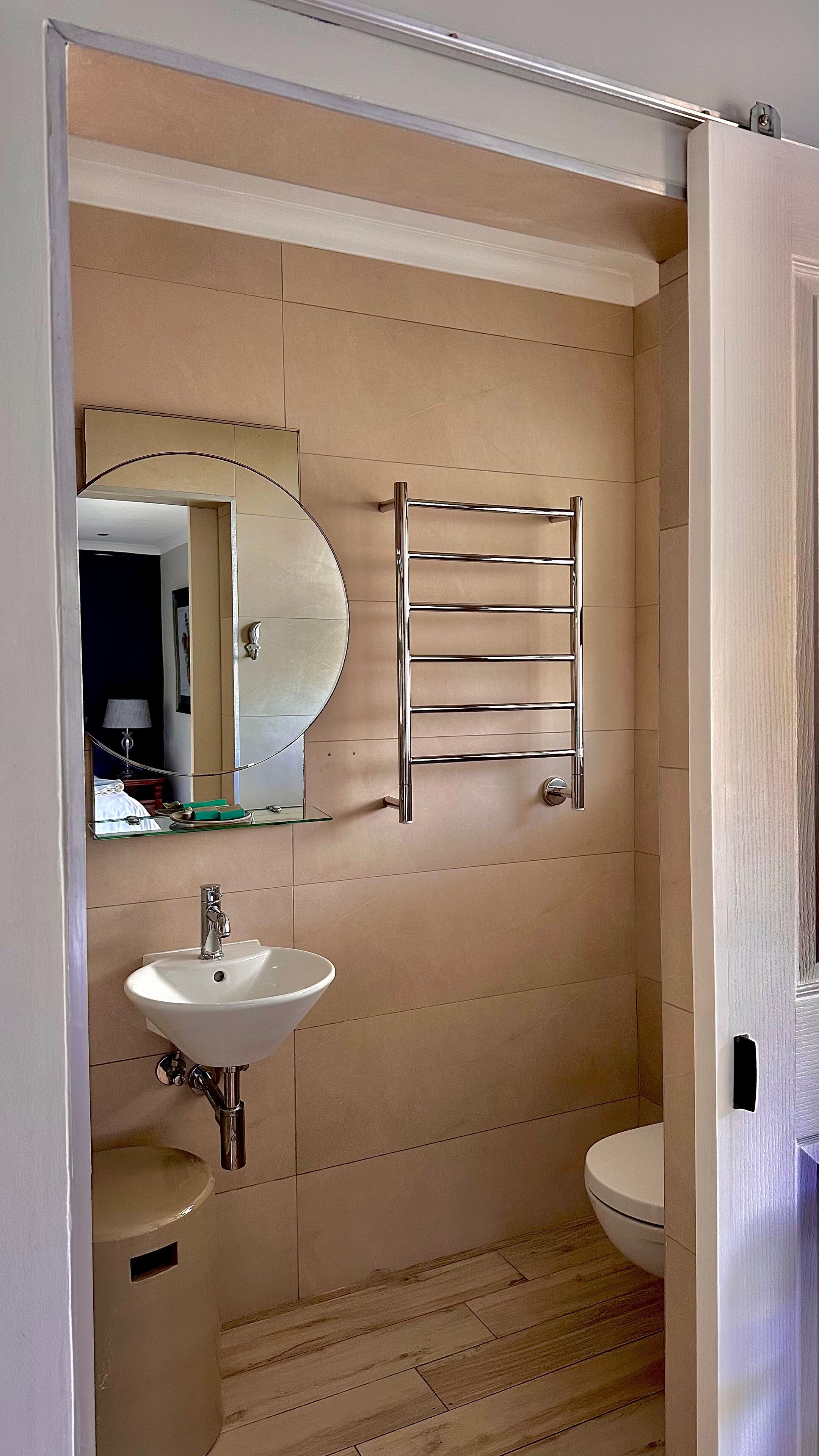 A bathroom with a sink, mirror, towel rack, and toilet.