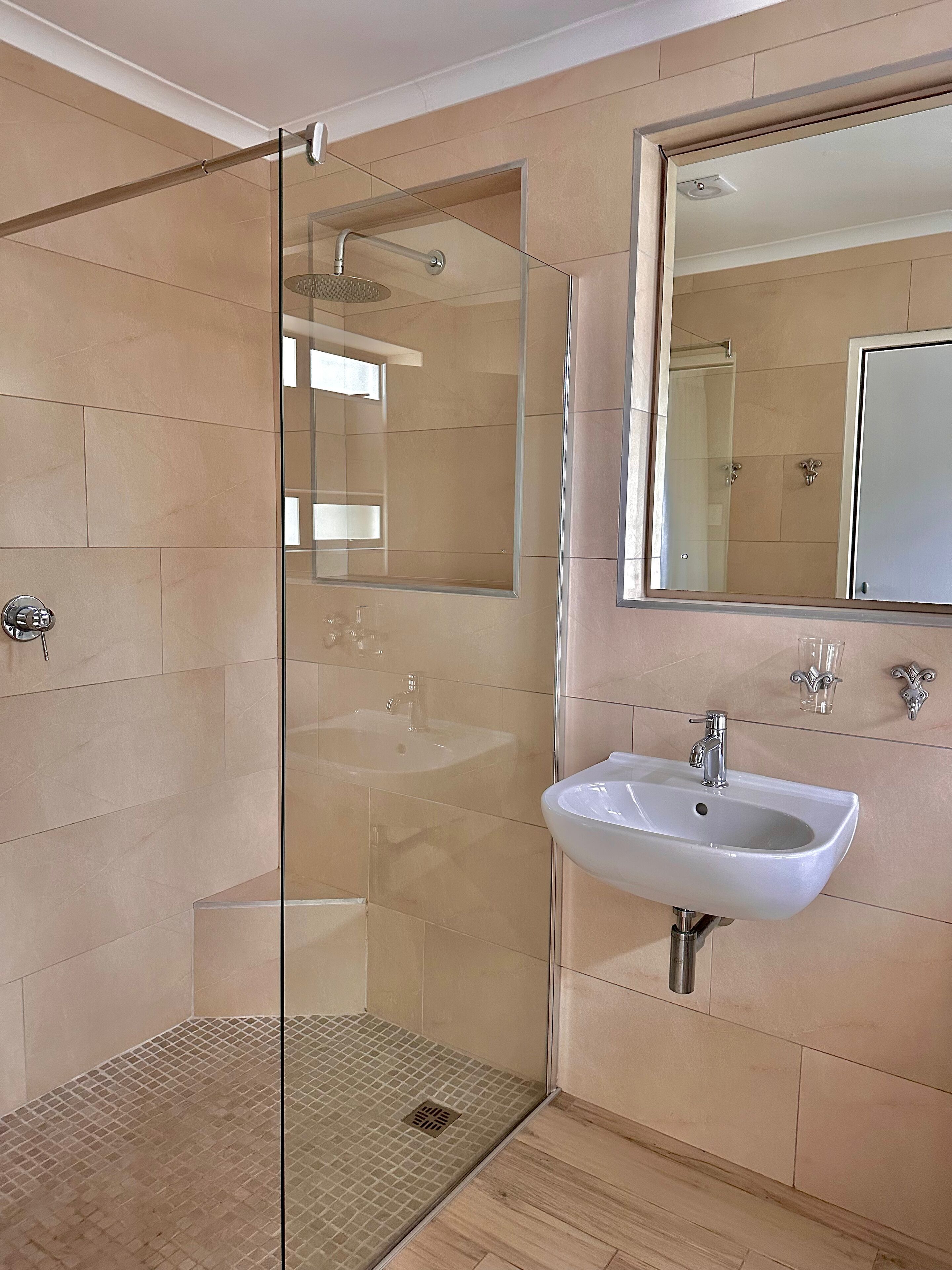 Une salle de bain moderne avec une douche à parois de verre, un lavabo blanc et un grand miroir.
