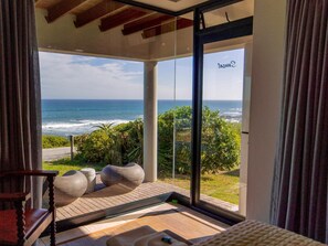 A room with a large glass door leading to a balcony overlooking the ocean. - Sawubona Guesthouse (Gqeberha (Port Elizabeth))