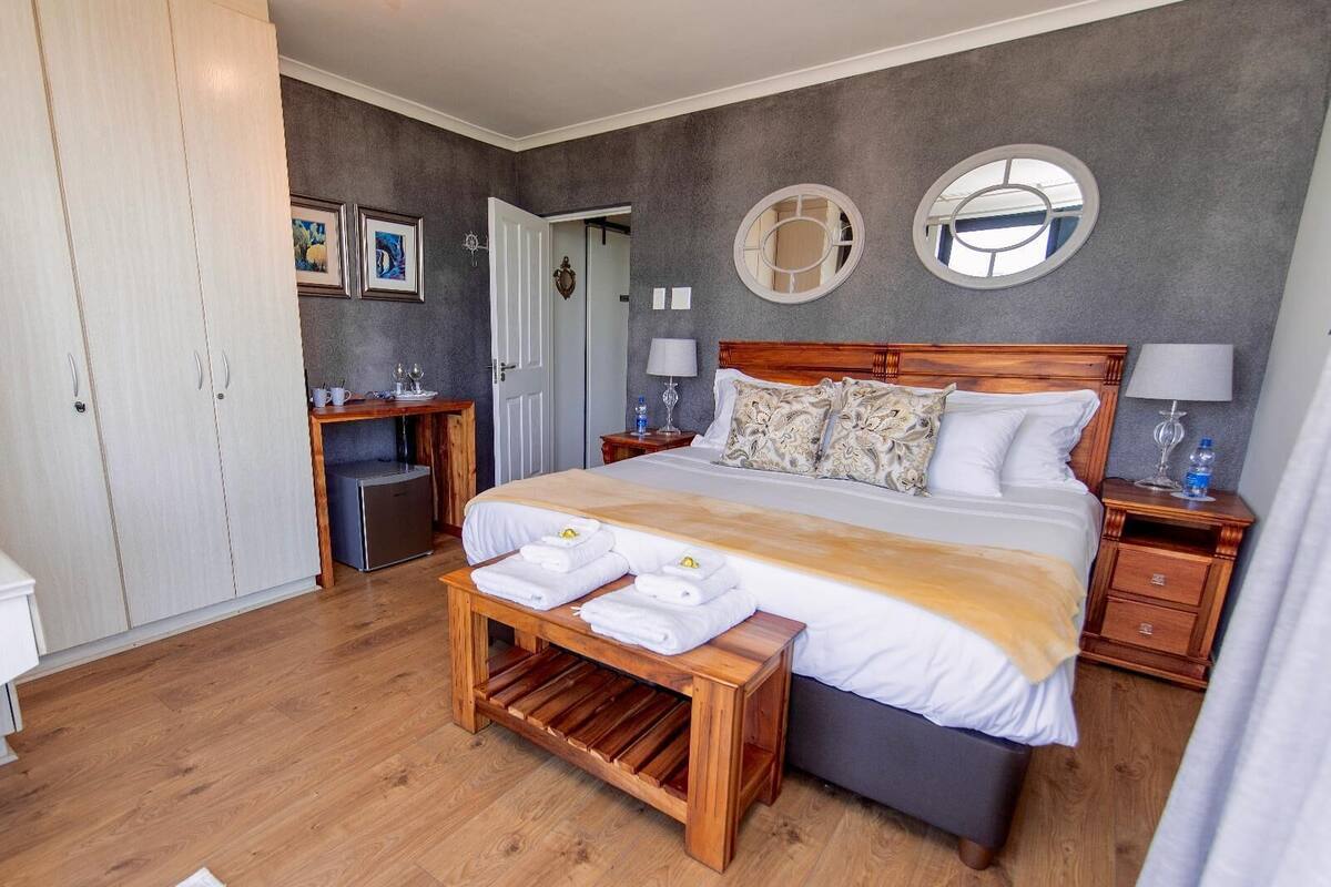 Une chambre à coucher avec un grand lit, des tables de chevet, une armoire, un bureau et un banc.