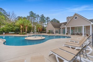 Relax by the tranquil pool surrounded by lush greenery and lounge chairs.