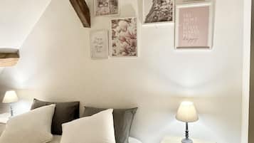 Ein Schlafzimmer mit Bett, Kissen, einem Nachttisch und Wandbildern.