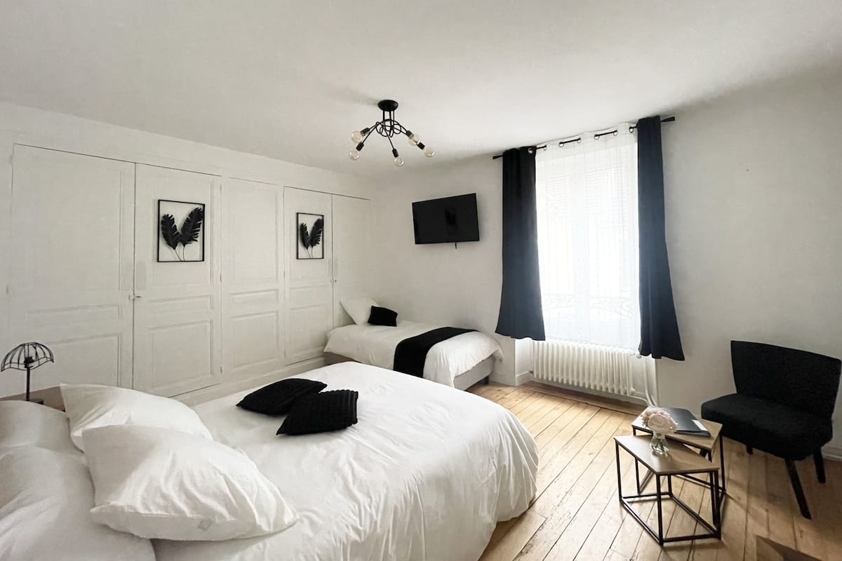 A bedroom with two beds, a TV, a chair, and a small table.