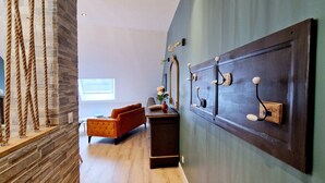 A modern interior with a stone accent wall, a wooden floor, a dark wall-mounted cabinet, and a large mirror. - Appartement Tout Neuf, Tout Cocooning et Tout Équipé Pour un Excellent Séjour (Laon)