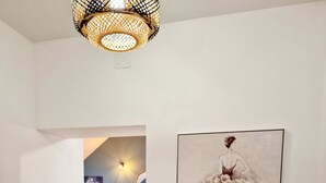 A hallway with a wooden cabinet, a framed painting, and a hanging light fixture. - Appartement Tout Neuf, Tout Cocooning et Tout Équipé Pour un Excellent Séjour (Laon)