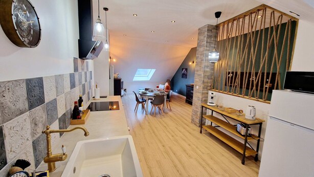A modern kitchen with a large sink, a dining area with a table and chairs, and a loft-style living space with a view. - Appartement Tout Neuf, Tout Cocooning et Tout Équipé Pour un Excellent Séjour (Laon)
