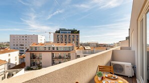 Une terrasse sur le toit, avec une table dressée pour le petit-déjeuner, d’où l’on peut admirer un panorama sur la ville, avec ses bâtiments et une grue de construction.