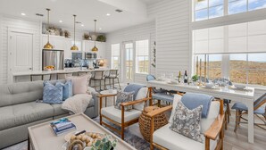 A spacious living area with a sofa, chairs, a coffee table, and a dining table set for a meal. - Luxury beachfront home with ocean views, pool, EV charger, chef's kitchen & golf (Port Aransas)