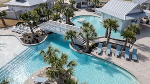 A resort with a large swimming pool, palm trees, and beach chairs. - Luxury beachfront home with ocean views, pool, EV charger, chef's kitchen & golf (Port Aransas)