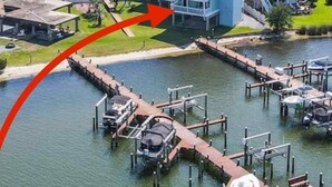 A coastal hotel with multiple buildings, a marina with boats, and a clear view of the ocean.