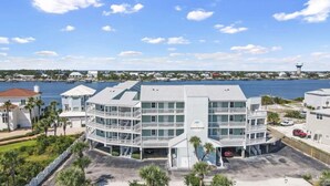 A multi-story hotel with a waterfront view, featuring balconies and a parking area.