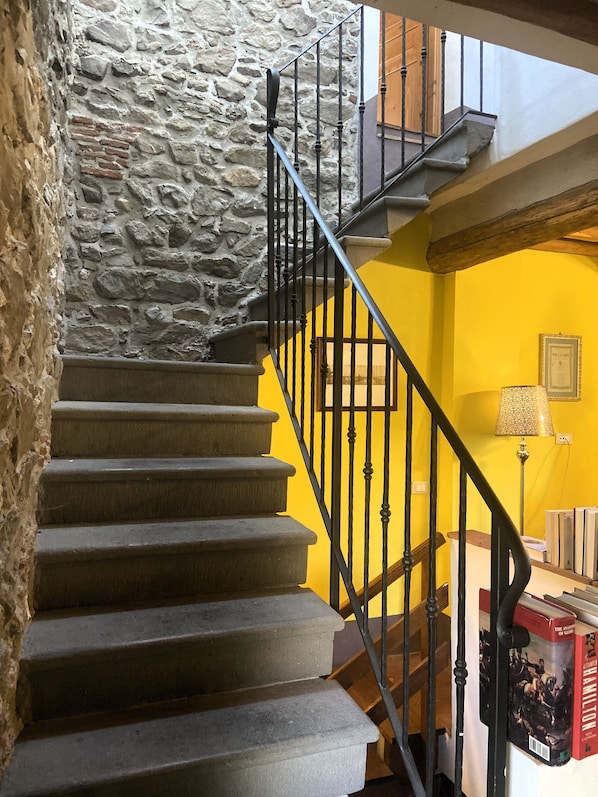 Un escalier avec des murs en pierre et un mur jaune.