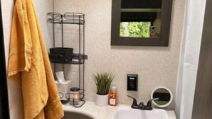 Un bagno compatto con lavandino bianco, specchio, porta asciugamani e water.