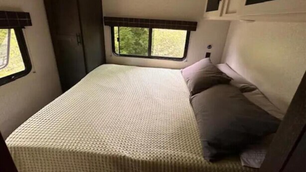 Interni di un camper compatto con un letto, una finestra e un angolo cottura.