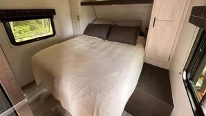 Camera a letto compatta in un camper, con un letto a castello, un'angusta finestra con vista e un angolo cottura.