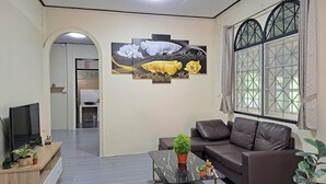 Un salon avec un canapé, une table basse ornée de plantes, un téléviseur et un tableau accroché au mur.