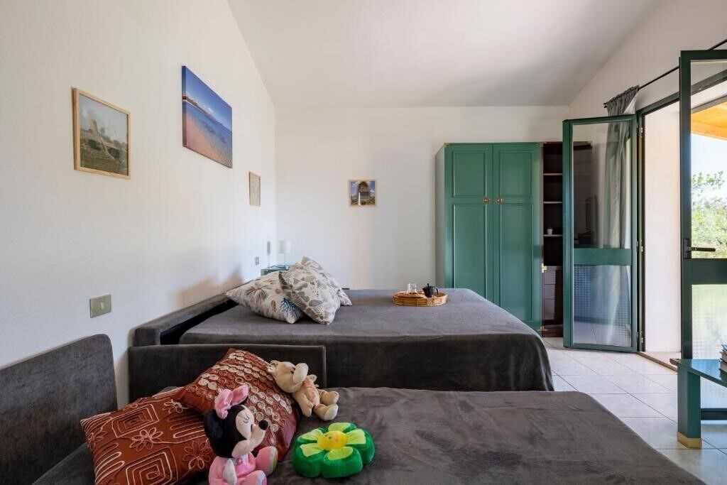 A room with two beds, a green wardrobe, and a sliding glass door leading to an outdoor area.