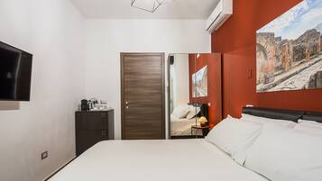 Een hotelkamer met een bed, een kledingkast, een bureau met een lamp en een televisie.