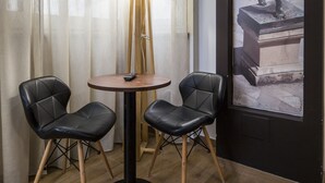 Ein Zimmer mit einem runden Tisch, zwei schwarzen Stühlen, einer Stehlampe und einem gerahmten Kunstwerk, das eine Statue zeigt.