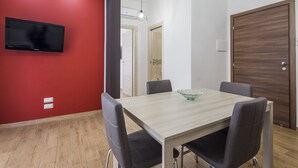 Ein stilvoller Essbereich mit einem hellen Holztisch, schwarzen Stühlen und einer roten Akzentwand.