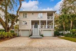 A two-story house with a front porch, a garage, and a driveway. - Updated Family Home, Steps to Beach, Private Heated Pool (Saint Simons Island)