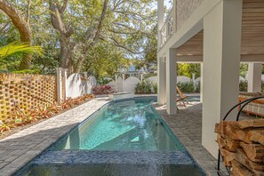A swimming pool with a tiled edge, surrounded by a brick wall and a white fence. - Updated Family Home, Steps to Beach, Private Heated Pool (Saint Simons Island)