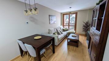 Una sala de estar moderna con una mesa de comedor, sofá y mueble para la televisión.