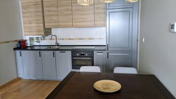 Una cocina moderna con armarios grises, una encimera de madera y una mesa de comedor con un mantel tejido.