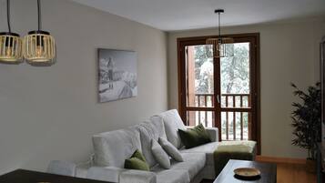 Una sala de estar con un sofá, una mesa de comedor y un ventanal grande.