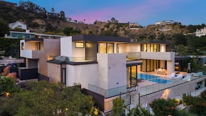 A modern two-story house with a large glass balcony and a swimming pool.