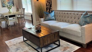 A living room with a sofa, coffee table, and dining area. - Relaxing 2-bedroom cottage in beautiful Sanford  (Sanford)