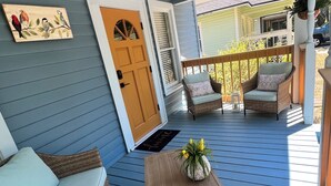 A covered porch with a ceiling fan, wicker furniture, and a wooden table with a vase. - Relaxing 2-bedroom cottage in beautiful Sanford  (Sanford)