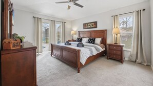 Ein Schlafzimmer mit einem hölzernen Bett, einem Nachttisch, einem Deckenventilator und einem Fenster mit Vorhängen.