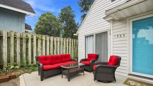 A patio area with a wicker sofa and chairs, a glass table, and a wooden fence. - ColorHouse | 1 mi to Mayo Clinic, No Stairs Entry (Rochester)