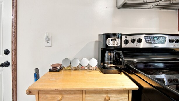 A kitchen with a black Cuisinart coffee maker, stainless steel stove, and a wooden countertop with jars. - ColorHouse | 1 mi to Mayo Clinic, No Stairs Entry (Rochester)