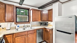 A kitchen with wooden cabinets, a stainless steel refrigerator, a microwave, a dishwasher, and a window with a view of greenery. - ColorHouse | 1 mi to Mayo Clinic, No Stairs Entry (Rochester)
