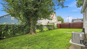 A residential backyard with a lawn, a tree, a fence, and an air conditioning unit. - ColorHouse | 1 mi to Mayo Clinic, No Stairs Entry (Rochester)