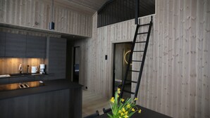 A modern kitchen with dark cabinetry, a built-in island, and a dining area with a table and chairs. - Cosy cottage in quiet surroundings in the southern Norwegian mountains (Bortelid)