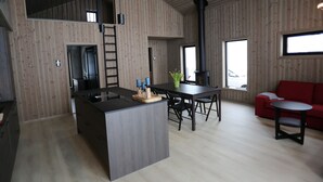 A modern kitchen with a central island, a dining area with a table and chairs, and a red sofa. - Cosy cottage in quiet surroundings in the southern Norwegian mountains (Bortelid)