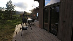 A wooden deck with outdoor furniture, a swing, and a glass door leading to a building. - Cosy cottage in quiet surroundings in the southern Norwegian mountains (Bortelid)