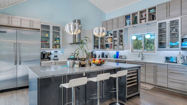A modern kitchen with a central island, bar stools, stainless steel appliances, and open shelving. - Beautiful East Hampton Home, Expansive Deck, Private Pool, Indoor/Outdoor... (East Hampton)